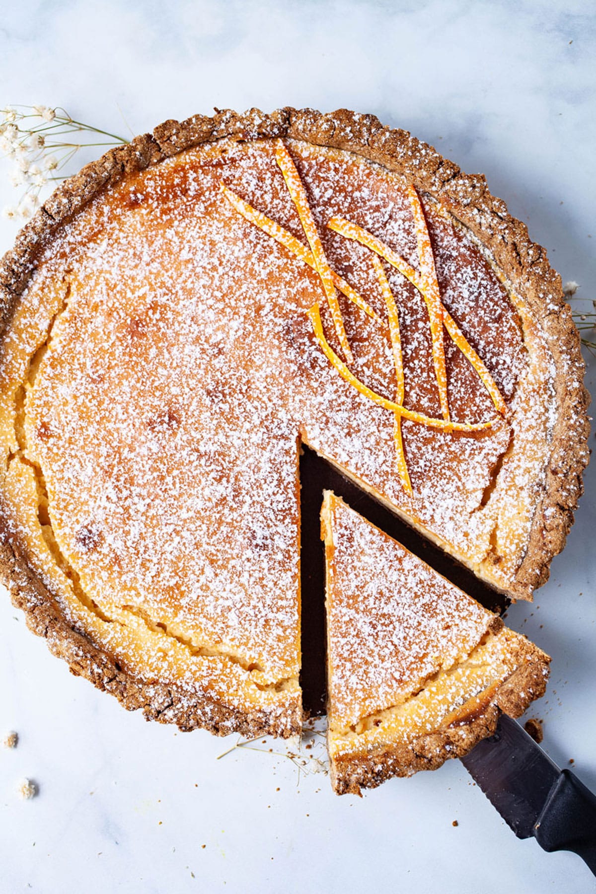 A piece lifted and taken out of a large ricotta pie.