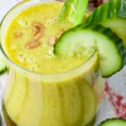 Creamy pineapple cucumber smoothie topped with seeds and garnished with extra cucumber slices.