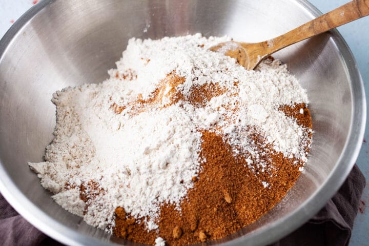 A spoon resting in a bowl with flour and brown sugar,