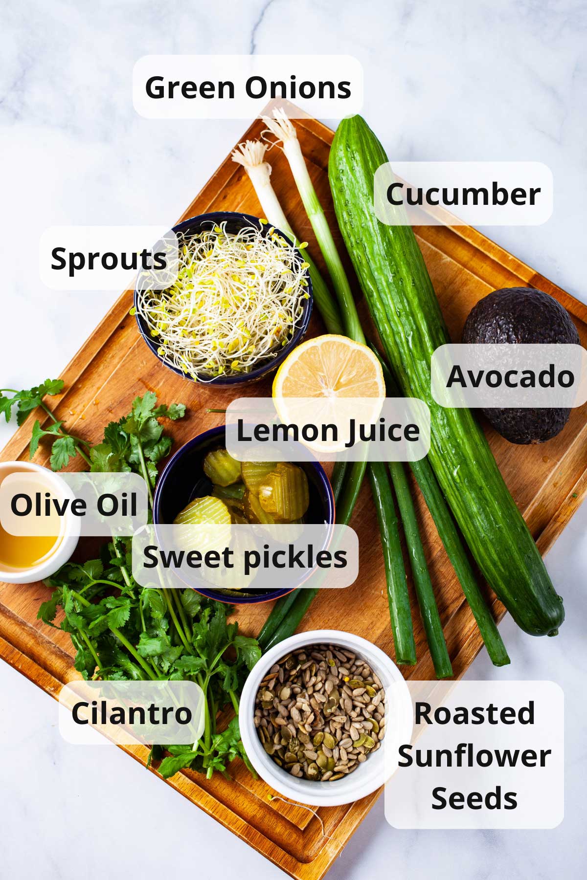 Ingredients to make a healthy cucumber salad displayed on a wooden board.