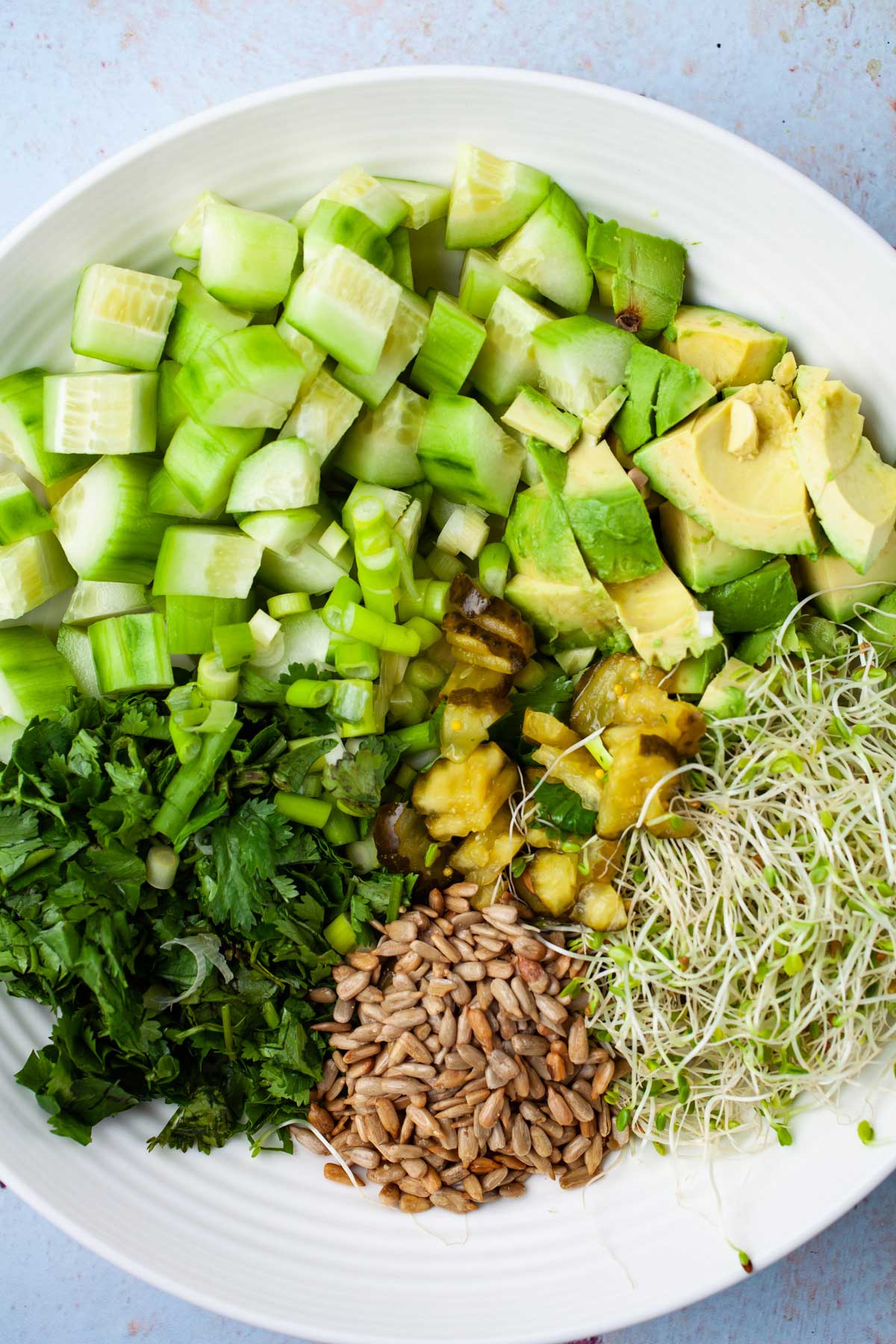 Chopped ingredients to make a healthy cucumber salad in a bowl.