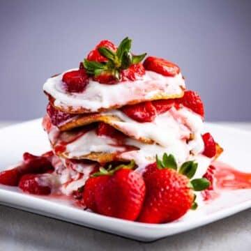 Pancakes stacked on top of each other and topped with strawberries and goat yogurt.