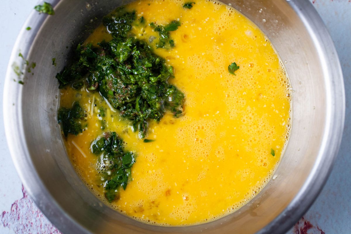 Blended eggs in a stainless steel bowl with a green parsley paste.