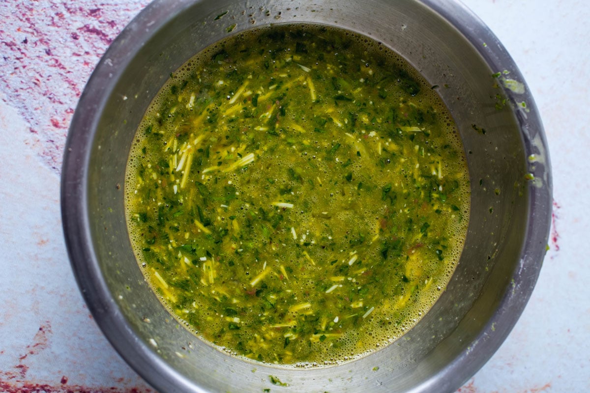 Mixed eggs, fresh parsley, and cheese in a bowl.