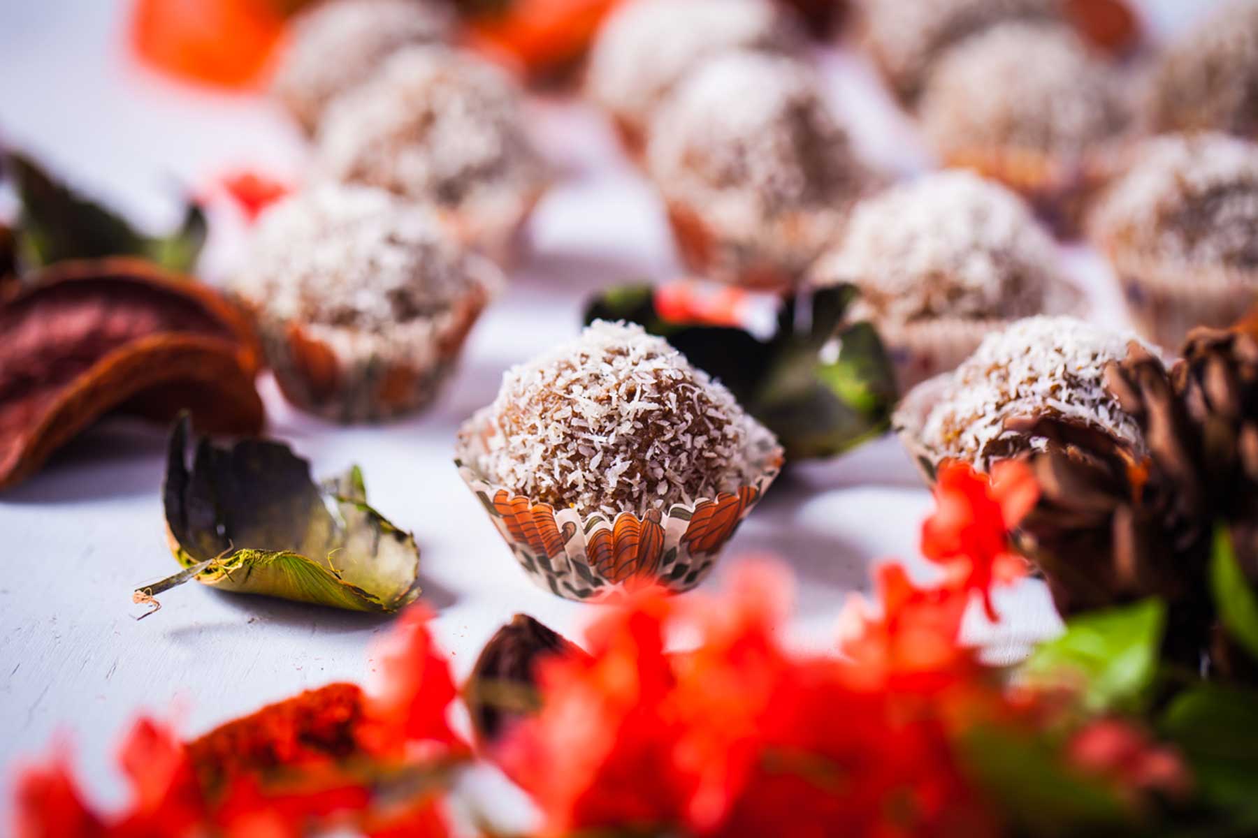 Coconut flakes coated bliss balls in mini cup holders.