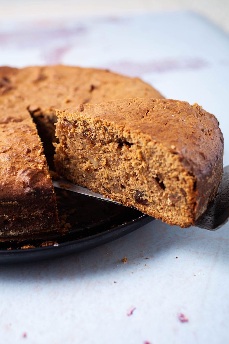 A slice is taken out of a coffee cake with a pie server.