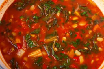 Homemade vegetable soup in a Dutch pan with rainbow chard and lima beans.