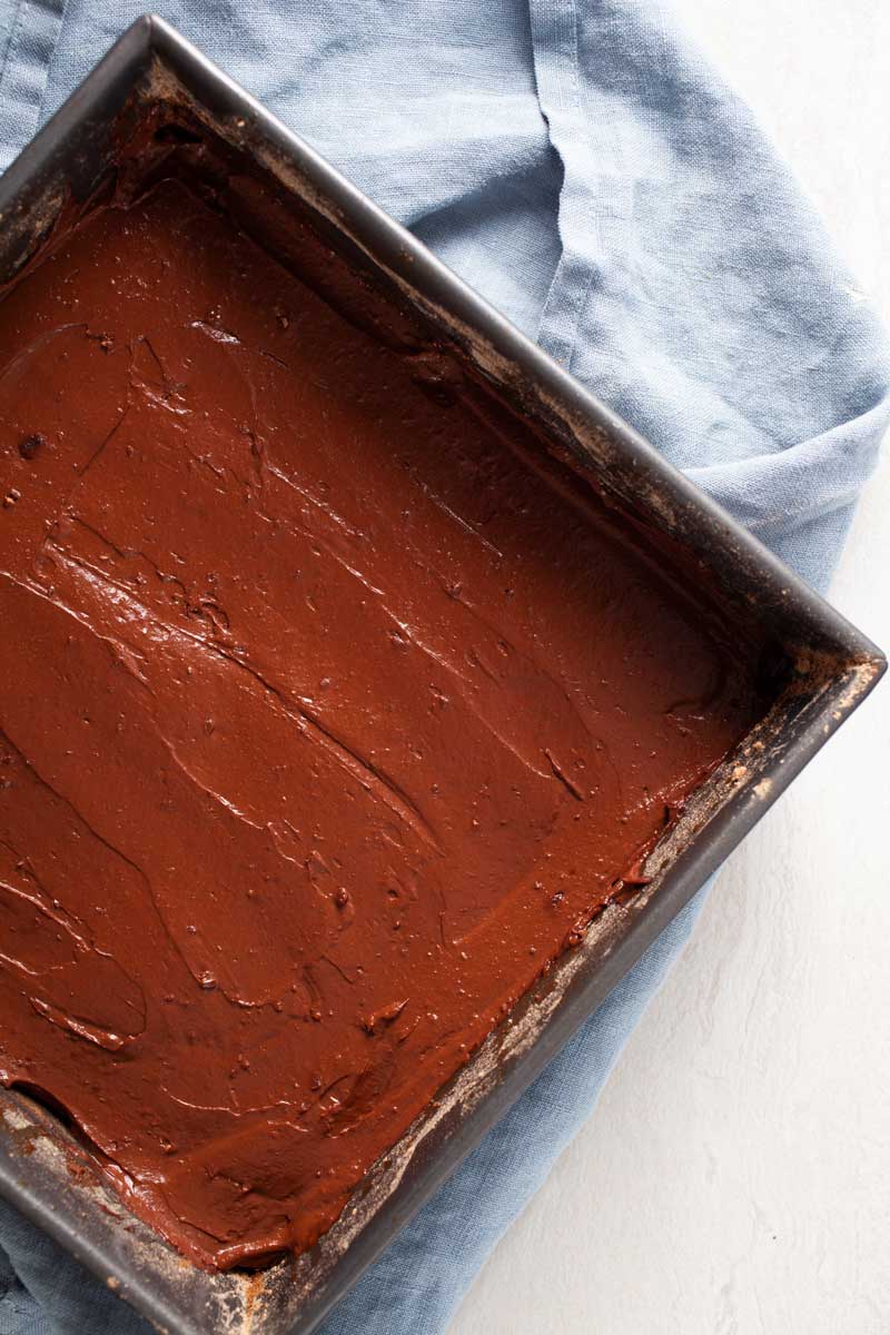 Creamy cacao batter in a baking pan to bake flourless chocolate brownies.