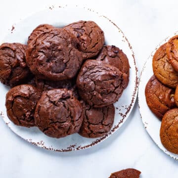 Two plates of soft baked brown peanut butter cookies stacked on top of each other.