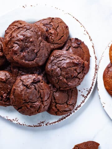 Two plates of soft baked brown peanut butter cookies stacked on top of each other.