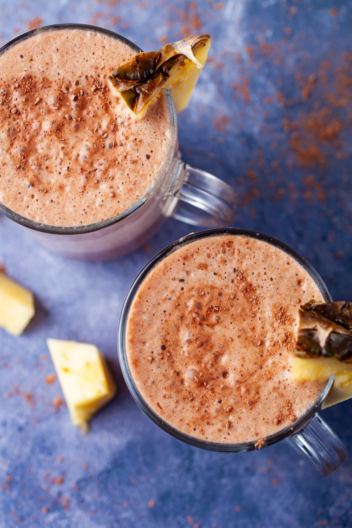 Creamy and frothy chocolate and pineapple smoothies topped with fresh pineapple slices.