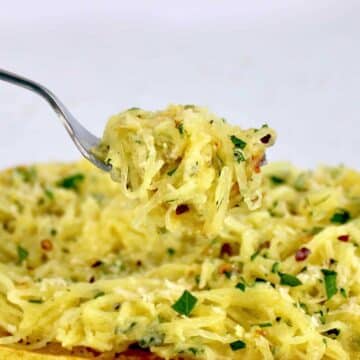 A fork taking a bite out of a bowl with spaghetti squash.