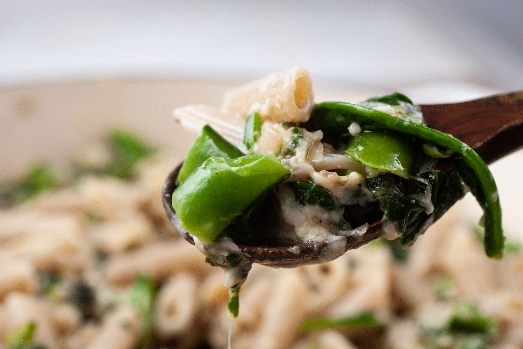 Garlic spinach pasta on a wooden spoon.