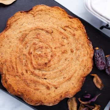 A baked date cake is displayed on a wooden board.