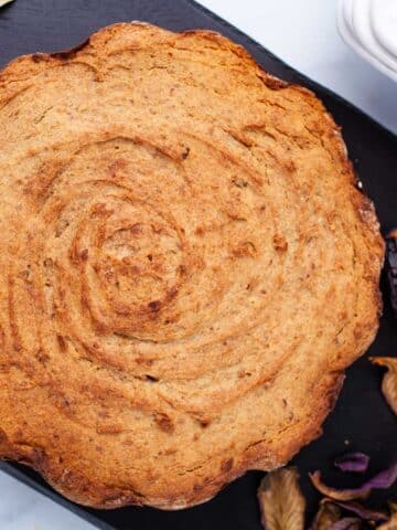 A baked date cake is displayed on a wooden board.