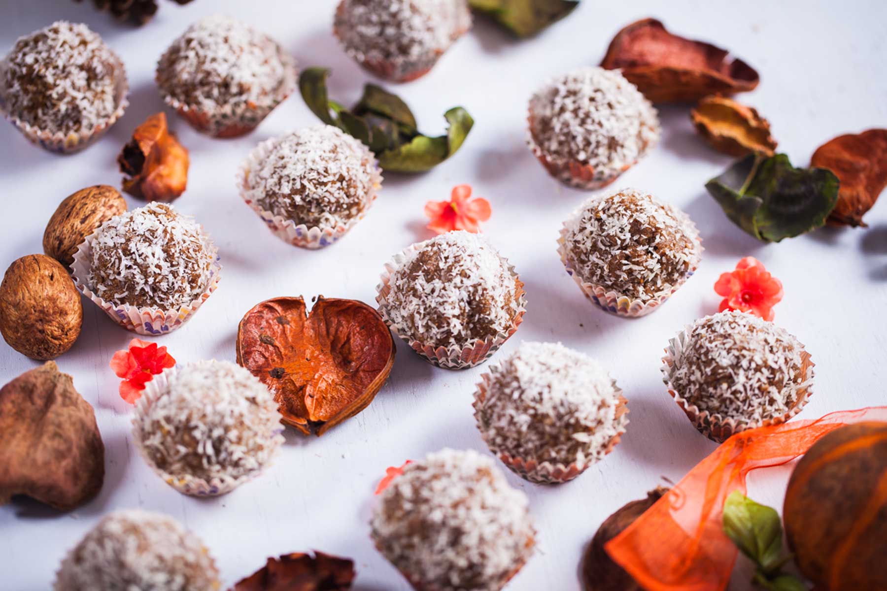 Coconut flakes coated bliss balls in mini cup holders.