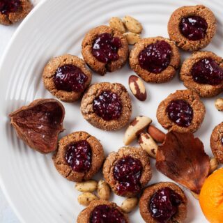 A plate filled with gluten-free almond flour cookies, topped with jam.