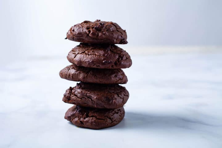 Dark brown chocolate peanut butter cookies stacked on top of each other.