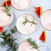 Grapefruit mocktails topped with Rosemary leaves served on a table.