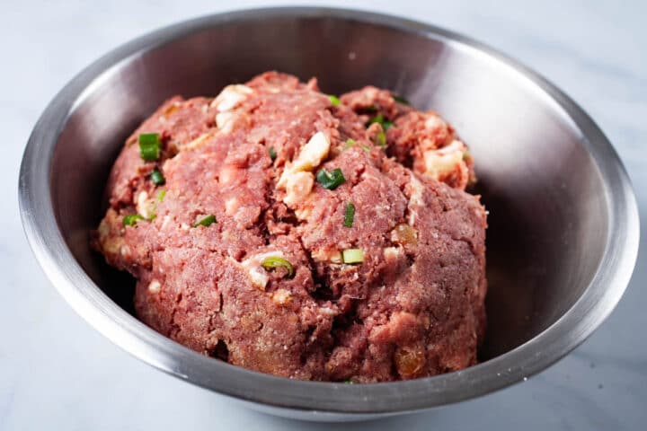 Beet and feta cheese seasoned ground beef in a stainless steel bowl in preparation for juicy gourmet burgers.