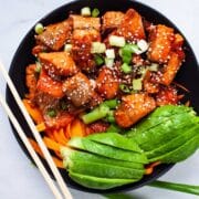 Cooked salmon poke bowl with avocado, carrots, and onions.
