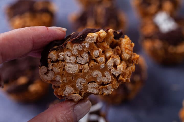 A hand holding half of a crispy and peanut butter filled rice crispy treat.