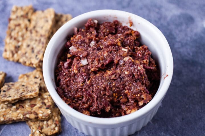Fig and olive tapenade displayed in a white ramekin and served with crackers.