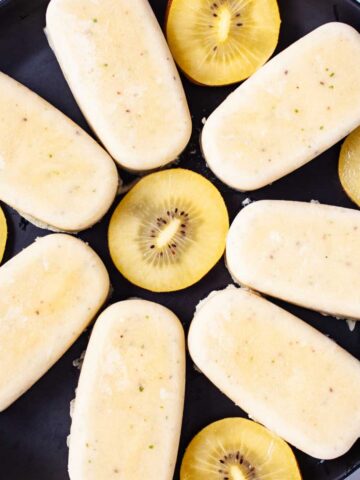 Healthy kiwi popsicles presented on a plate.