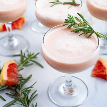 Grapefruit mocktails topped with Rosemary leaves served on a table.