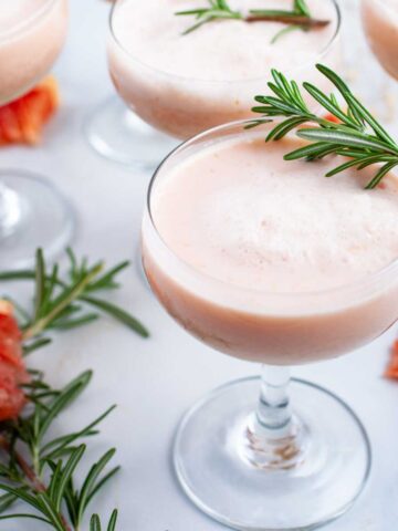 Grapefruit mocktails topped with Rosemary leaves served on a table.