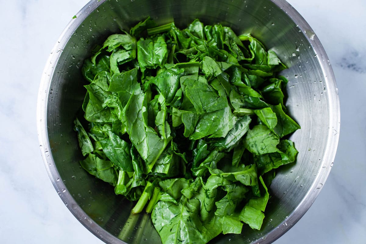 Chopped fresh spinach in a stainless steel bowl.