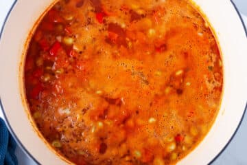 Lima beans and vegetable in a red tomato base soup in a Dutch pan.