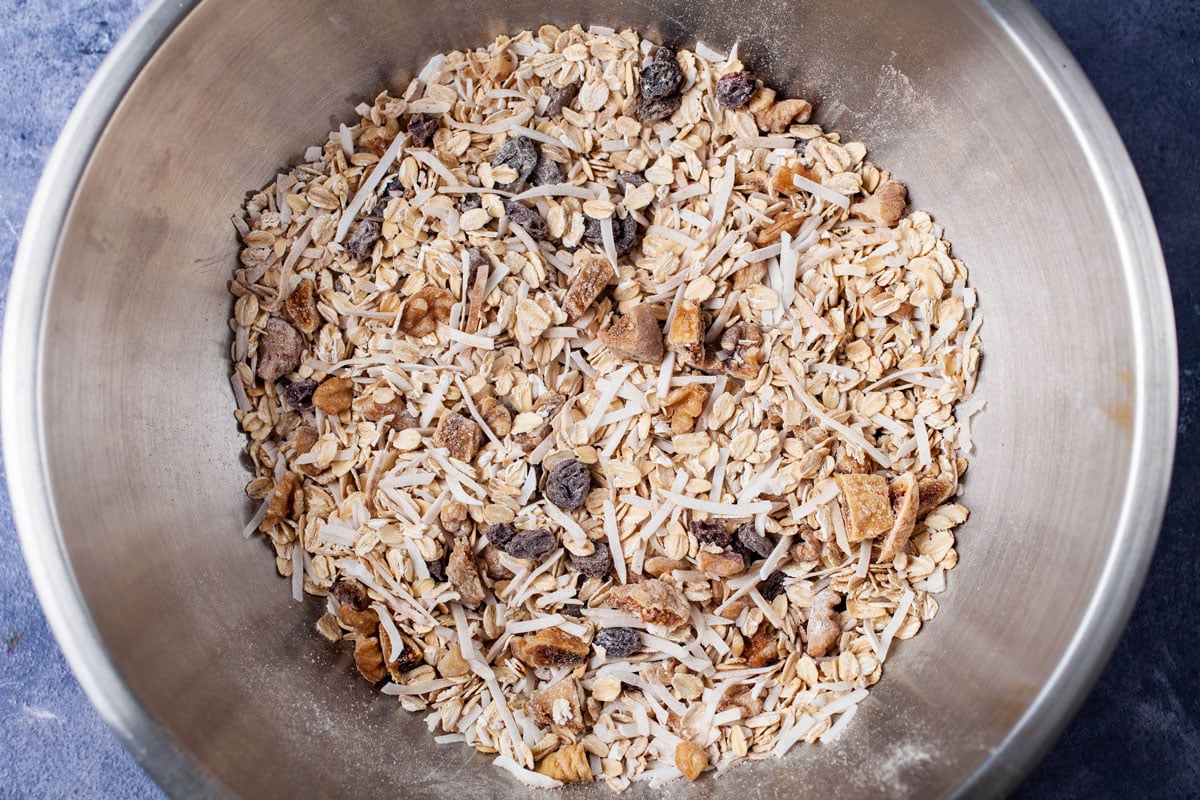 A stainless steel bowl containing a mixture of dried ingredients with oats.