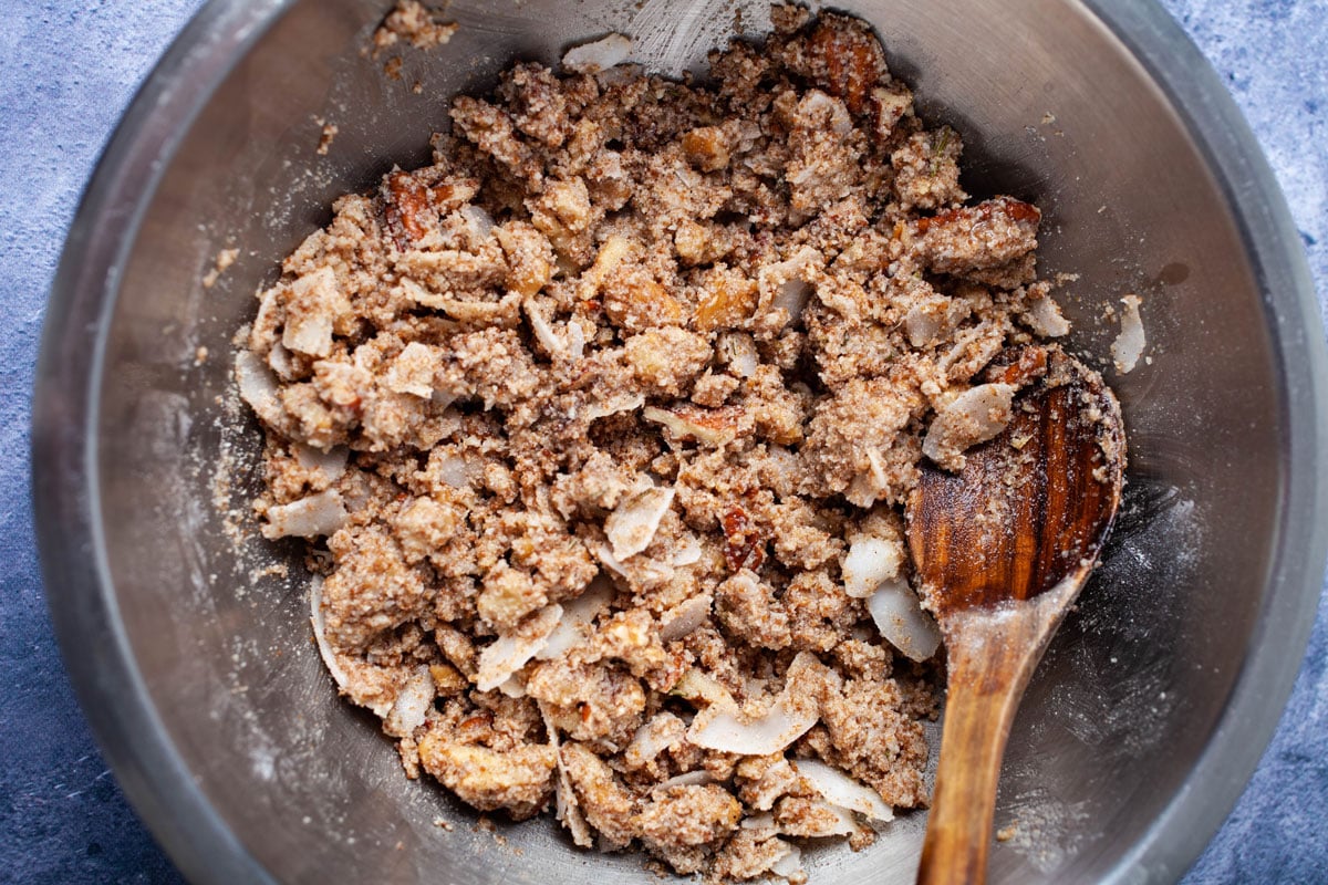 An oil coated flour and nut mixture in a stainless steel bowl.
