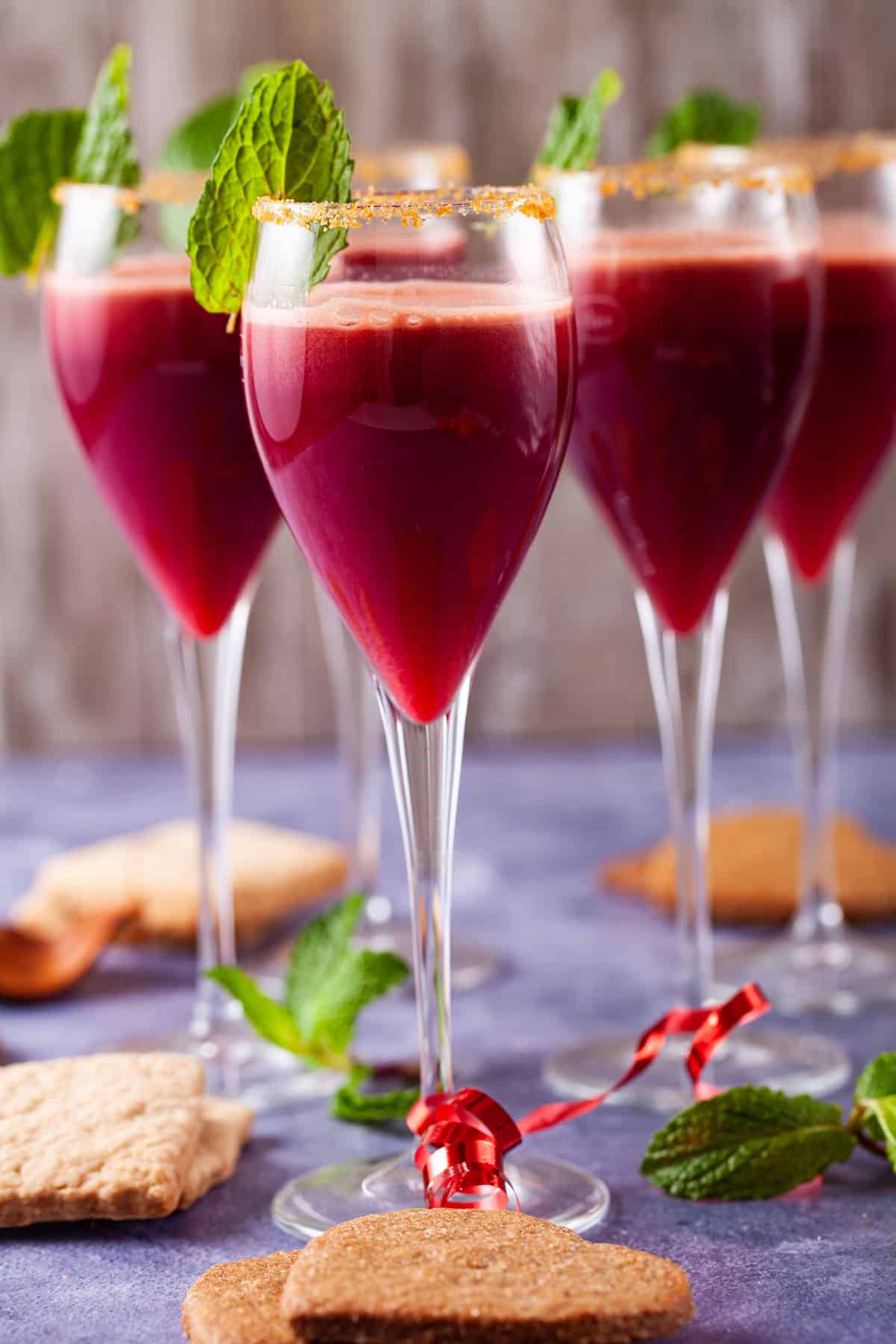 Elegant champagne glasses filled with a beautiful reddish pomegranate mocktail.