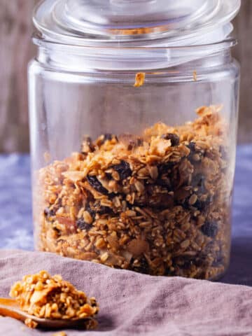 Baked granola stored in a wide-mouth glass jar.