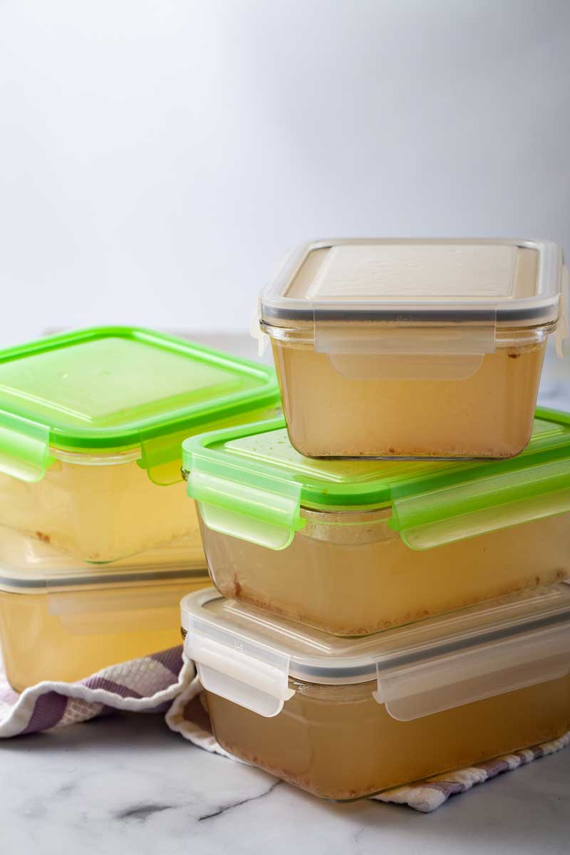 Five airtight containers filled with chicken stock.