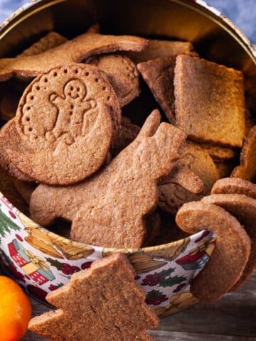 Different shaped brown cookies in a large Holiday cookie box.