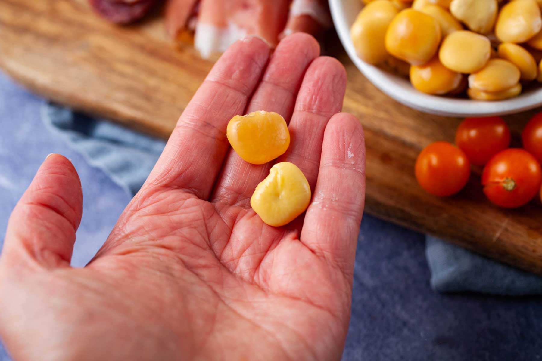 A hand holding a peeled lupini beans and its skin.