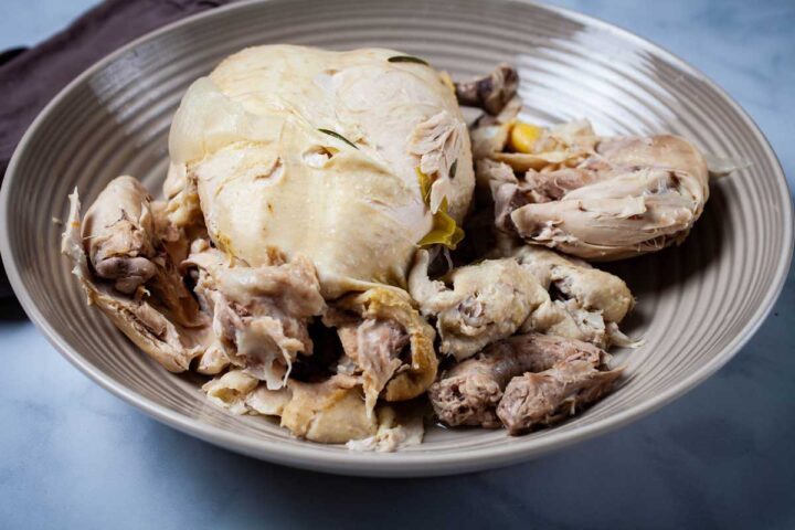 A large plate with a whole soft poached chicken.