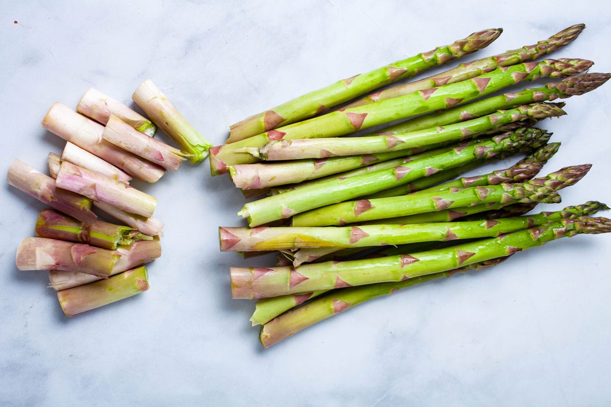 Asparagus resting on a table with ends chopped off.