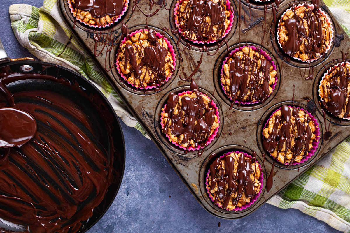 Rice crispy treats in cupcake holders covered with melted chocolate.