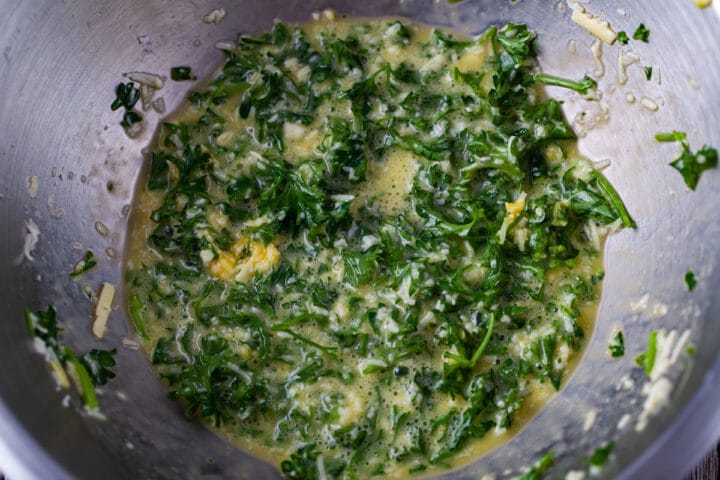 A close up of an egg parmesan and parsley mixture in a bowl.