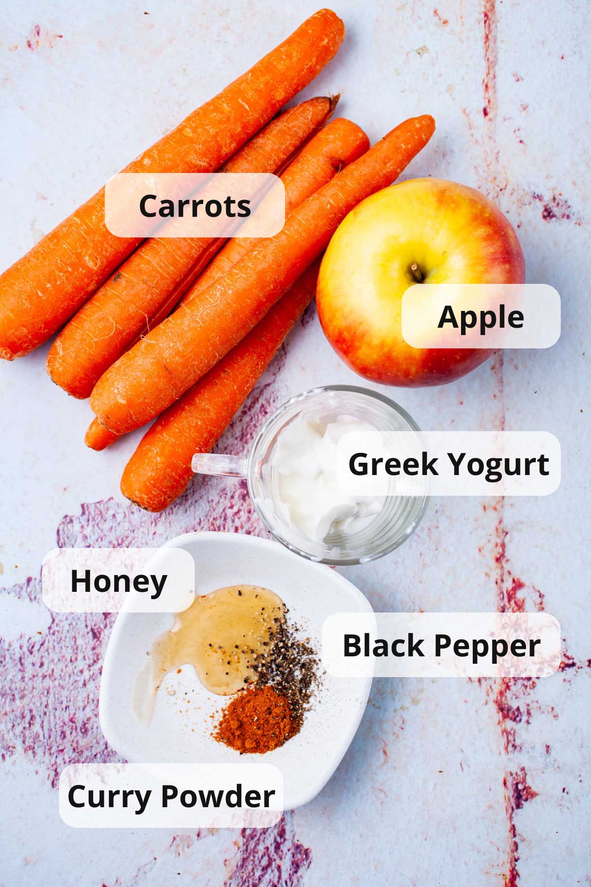 A series of ingredients on a table to make a raw carrot salad.