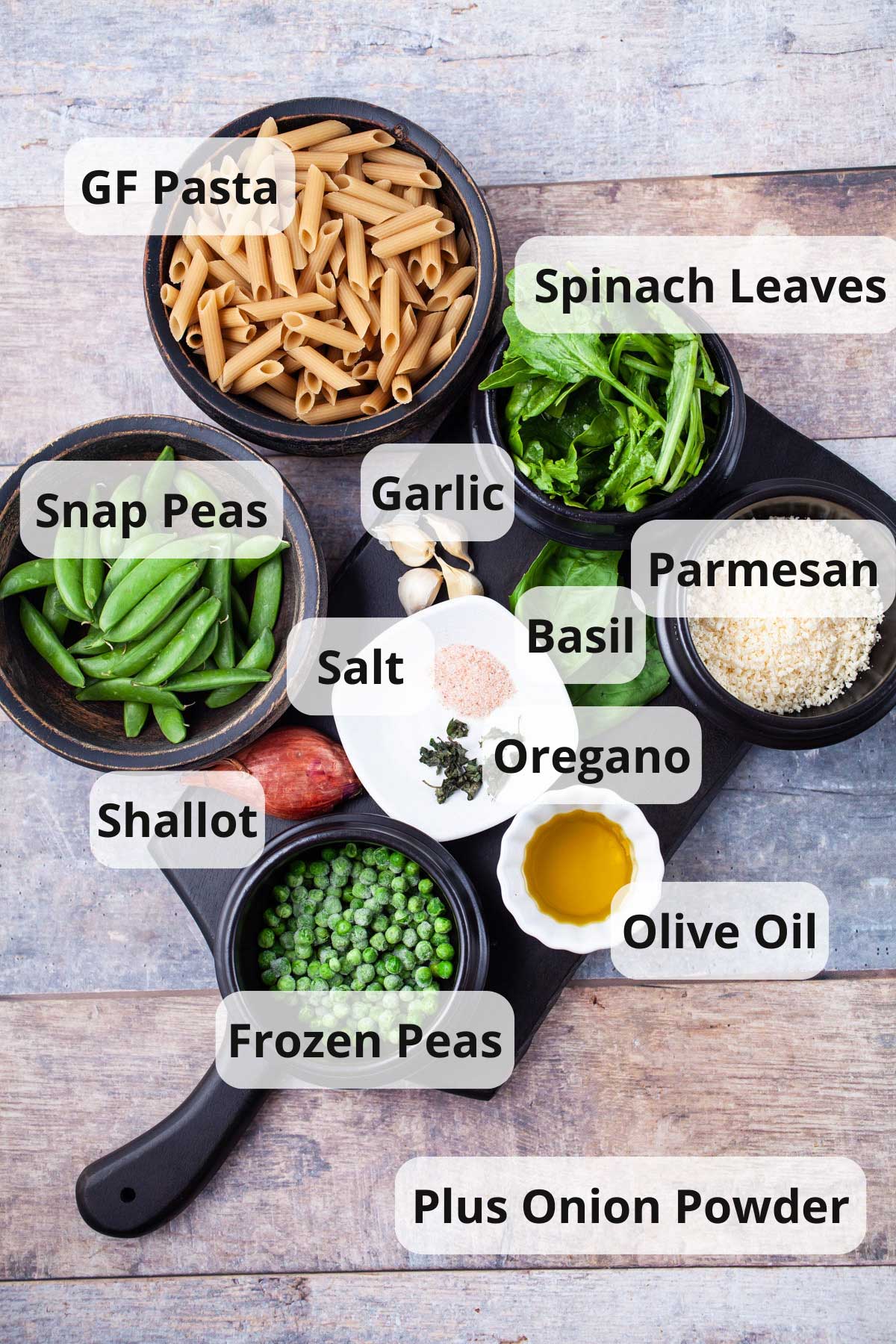 A series of ingredients displayed on a table to make a plant based pasta with peas.