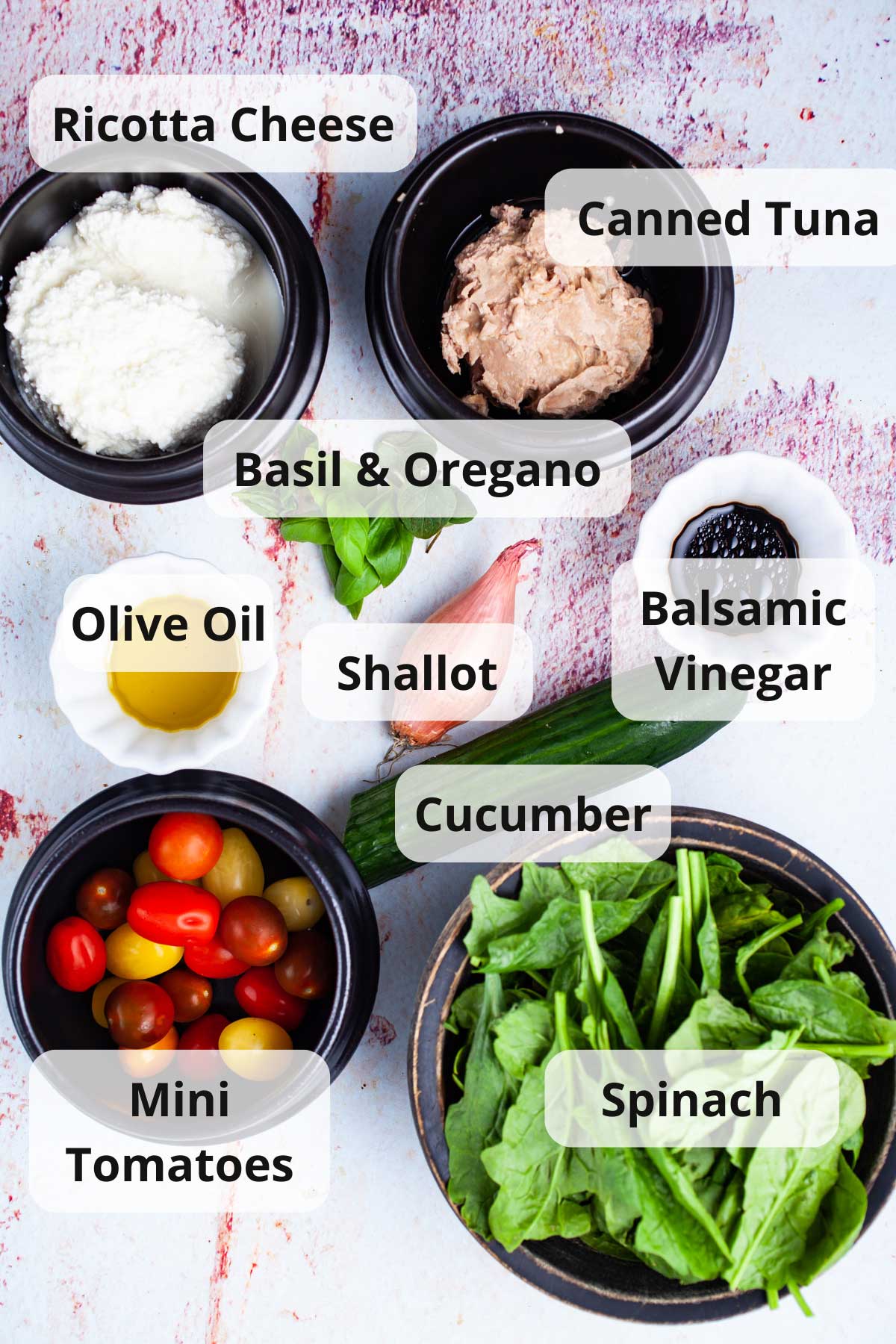 A series of ingredients on a table to make a tuna cucumber salad with ricotta cheese.