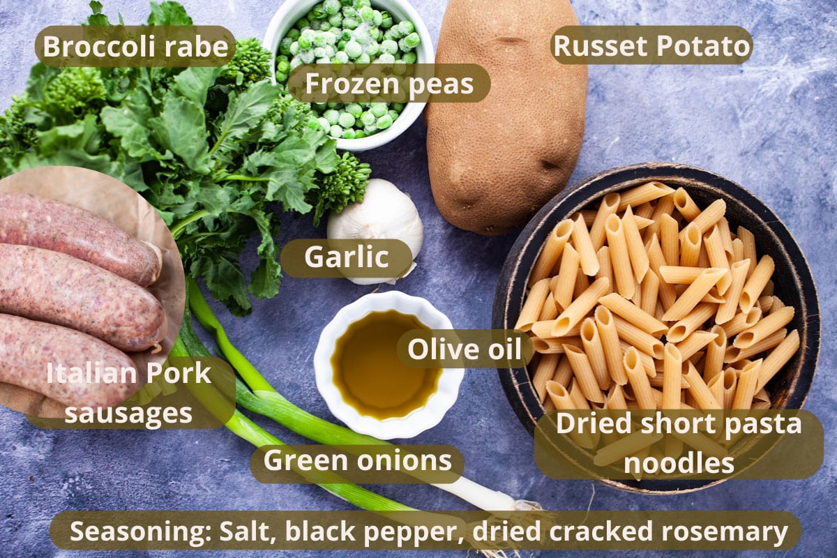 Uncooked penne, frozen peas, a bushel of broccoli rabe, olive oil, a large Russet potato, two green onions, and garlic displayed on a table.