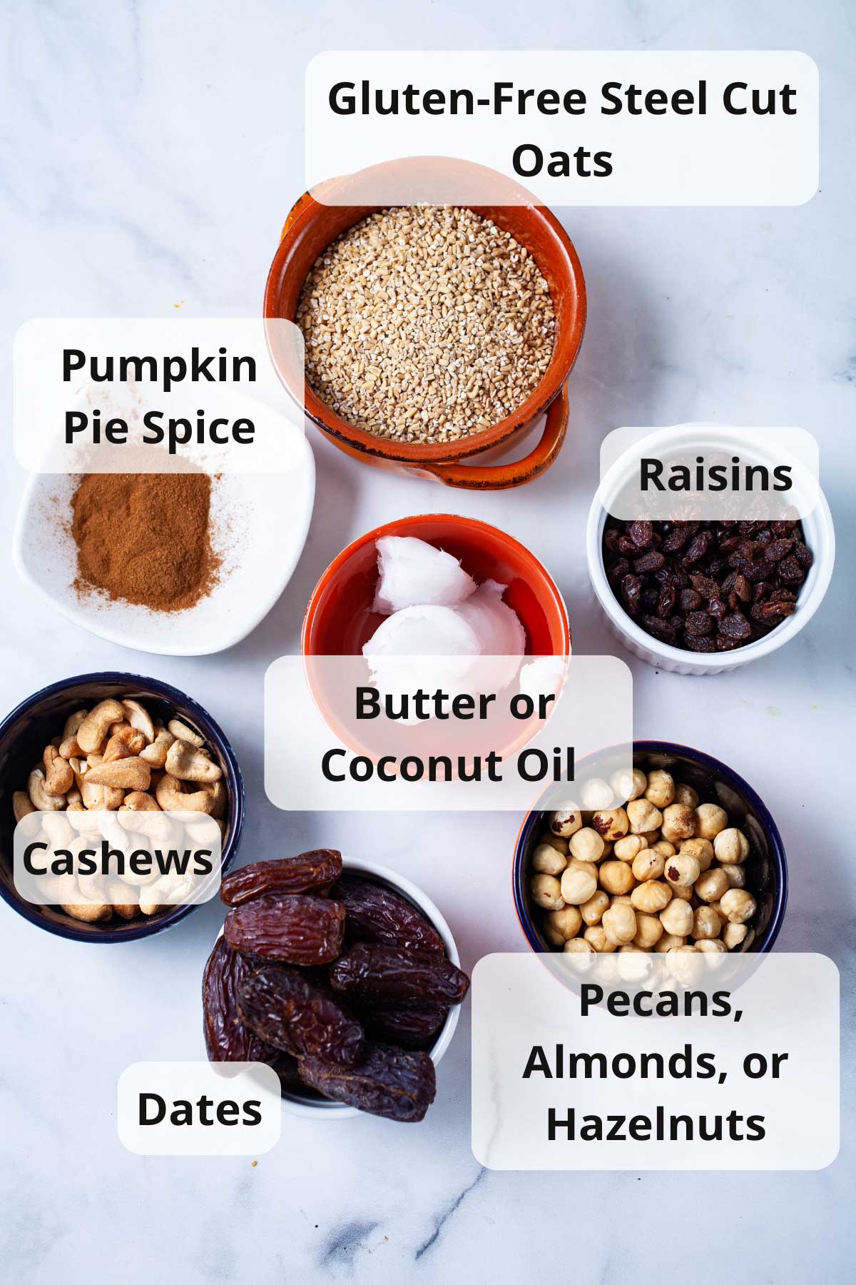 Oats, raisins, coconut oil, nuts, dates, and spices displayed on a table.