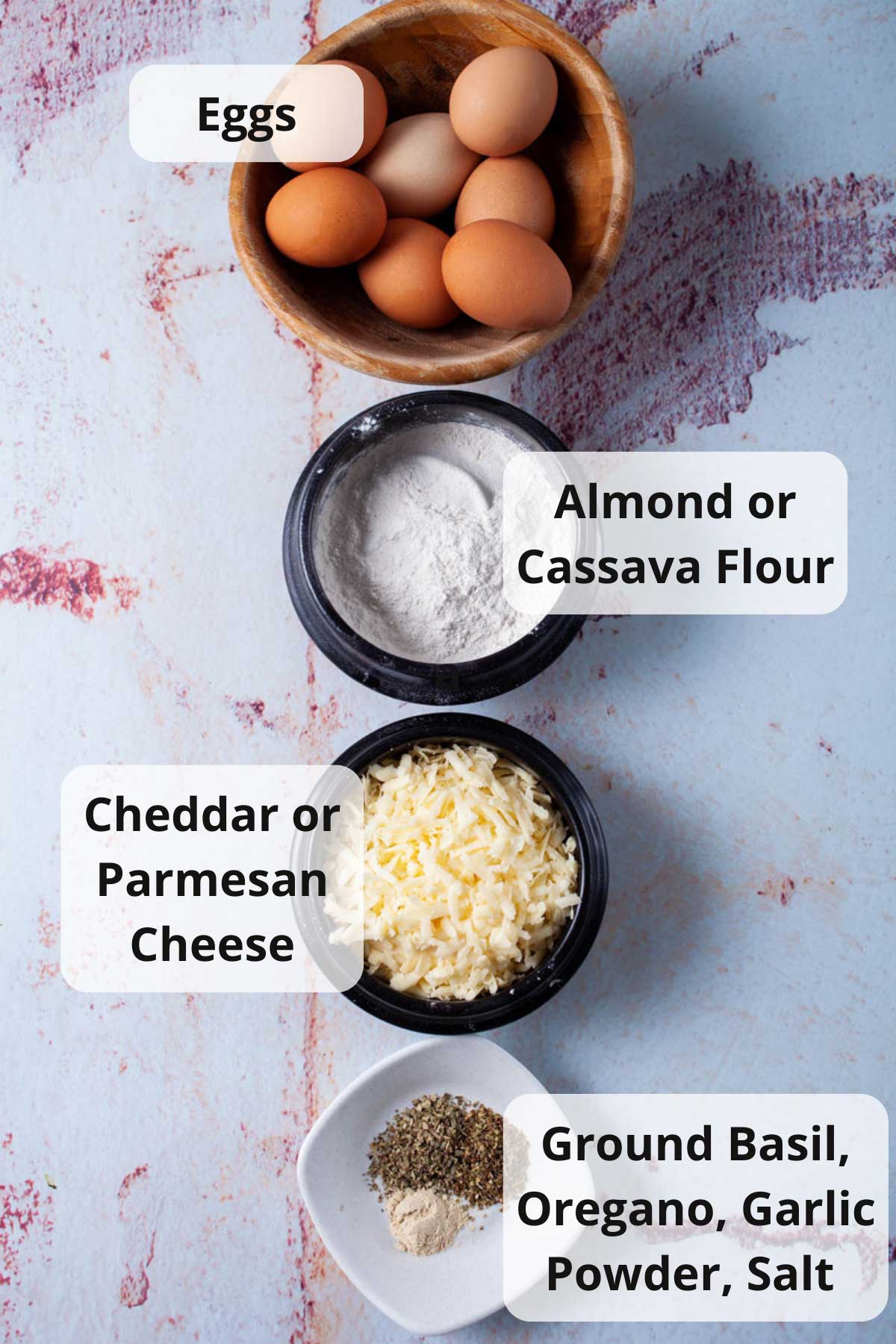 Eggs, almond flour, Parmesan cheese, and herbs displayed on a table.