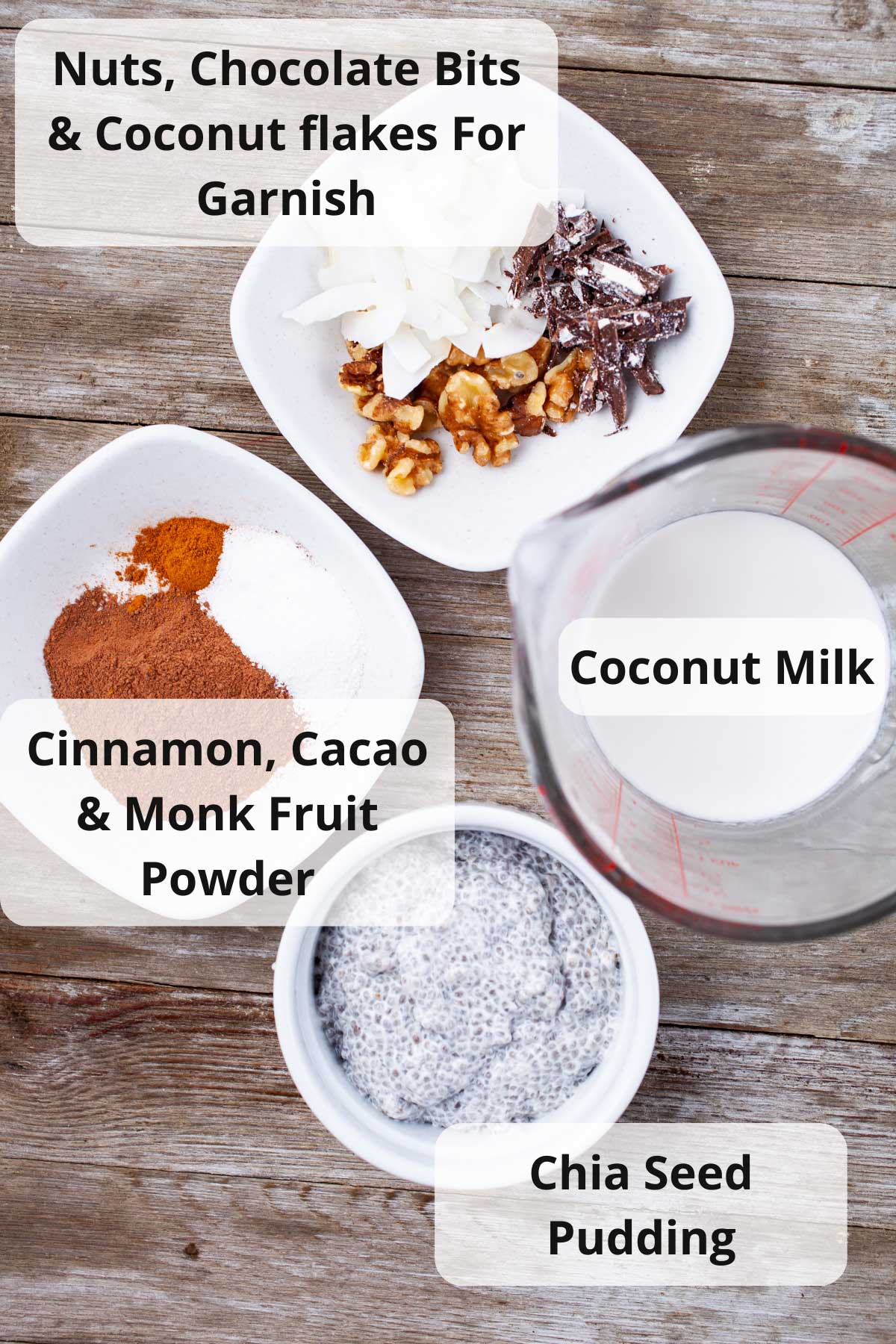 Nuts, chocolate bits, coconut flakes, coconut milk, cinnamon, cacao, Monk Fruit Powder, and chia seed pudding displayed on a table.